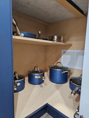 A kitchen with wooden cabinets and blue cookware.