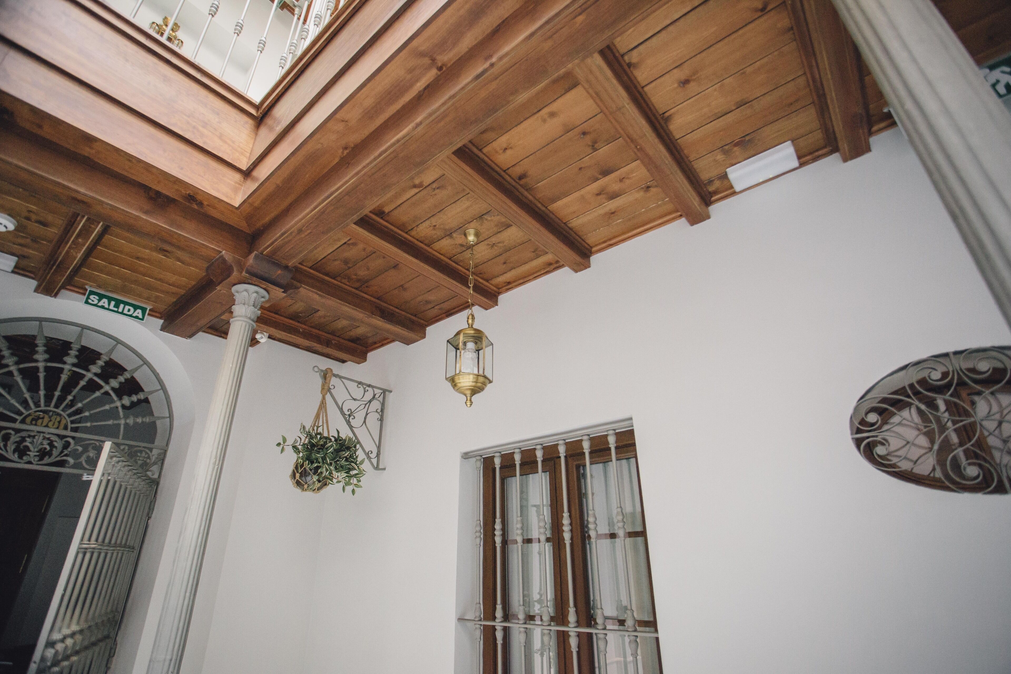 A wooden ceiling with a skylight, a sign reading "SALIDA," and a window with metal bars.