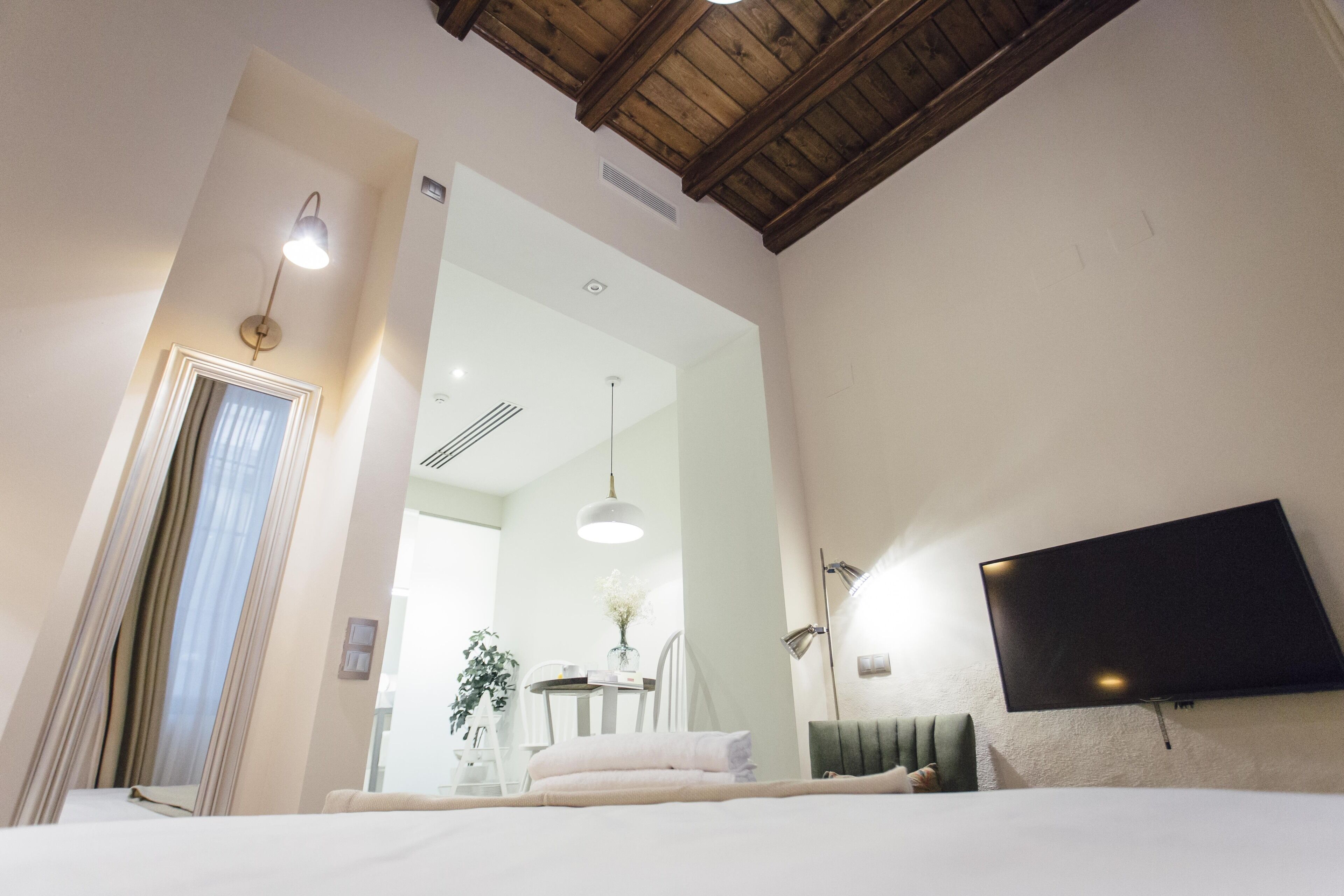 Een hotelkamer met een bed, een flatscreen televisie, een plafondventilator en een grote spiegel.