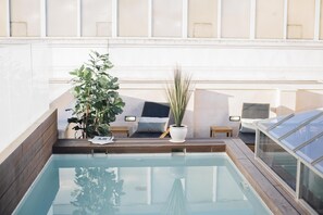 A rooftop pool area with a seating area, potted plants, and a glass enclosure. - One&Lux Byron Suites (Seville)