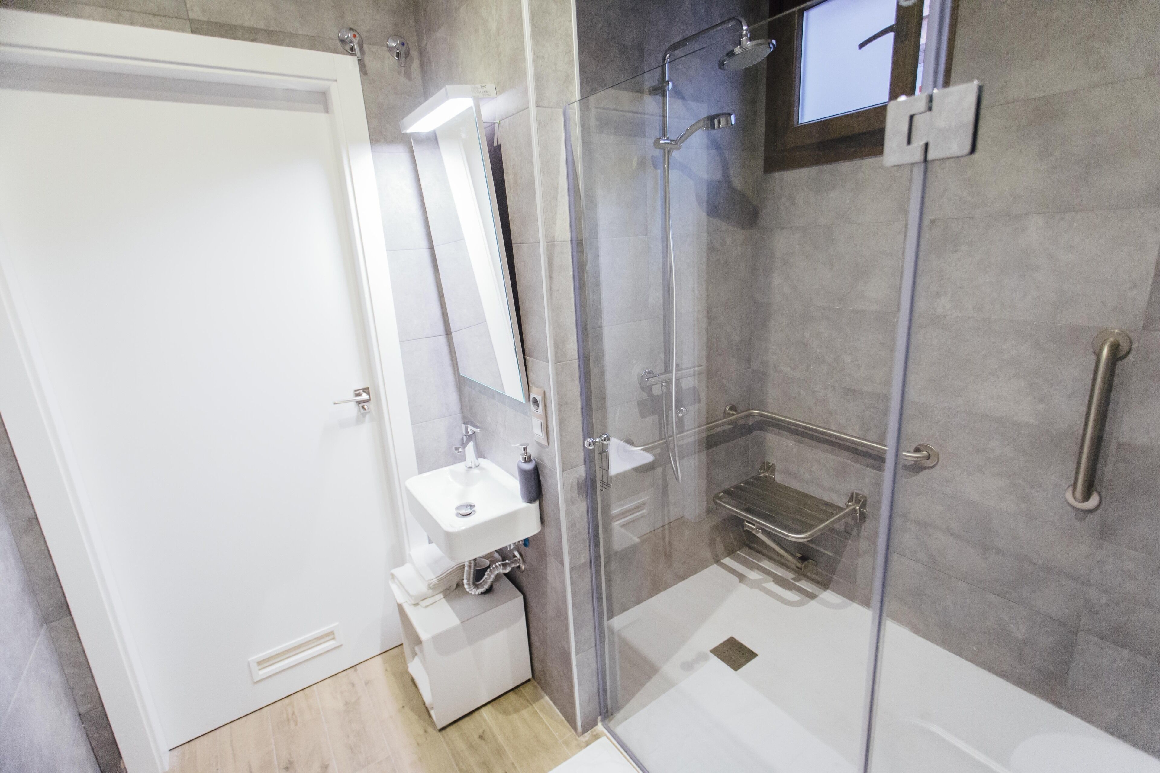 Un baño moderno con ducha de vidrio, lavamanos blanco y espejo.