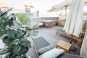 Una terraza en la azotea con sillones de descanso, un jacuzzi y una mesa de madera.