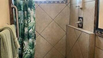 A small bathroom with a shower, a toilet, and a towel rack.