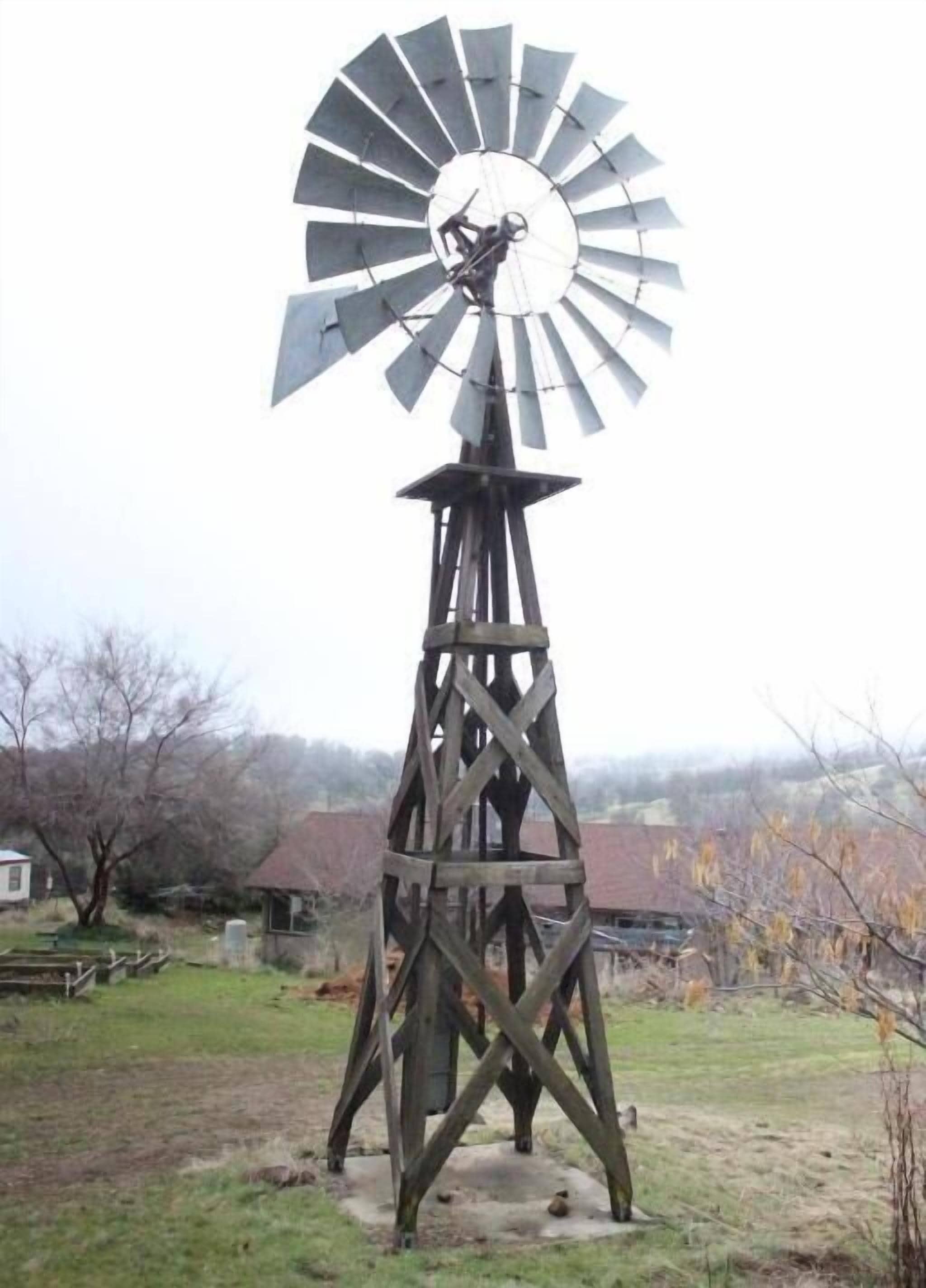 Eine Windmühle mit Holzkonstruktion und einem großen Flügel.