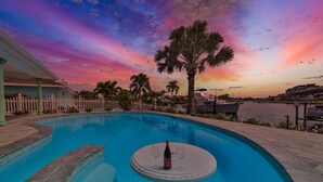 Ein Pool mit Sonnenuntergangsblick, Palmen und Uferlage.