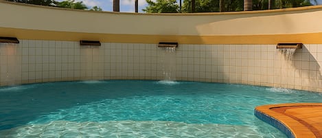 A clear blue pool with a tiled edge and a curved wooden deck.