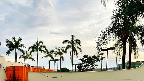 A swimming pool with a tiled deck, surrounded by palm trees and a clear sky. - Elegance Suites Franca (Franca)