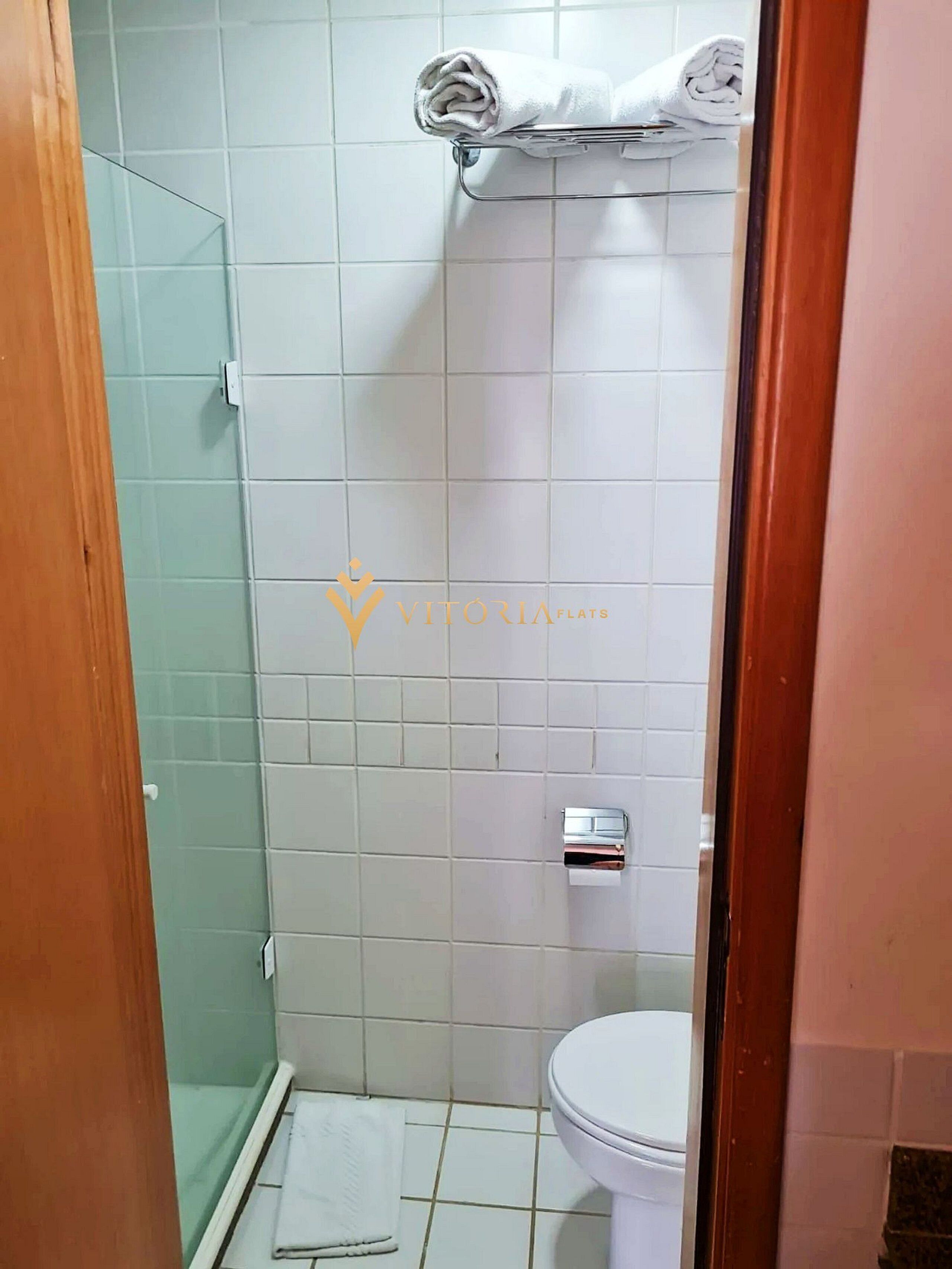 A bathroom with a shower, toilet, and a towel rack.