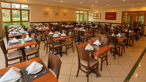A spacious dining area with multiple tables set for service, large windows offering views of the outdoors, and a clean, modern interior design. - Elegance Suites Franca (Franca)