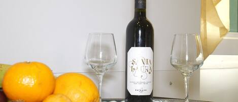Una botella de vino con etiqueta, dos copas de vino vacías y varias naranjas sobre una bandeja.