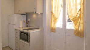Eine kleine Küche mit weißen Schränken, einem Einbauofen und einem Kühlschrank.