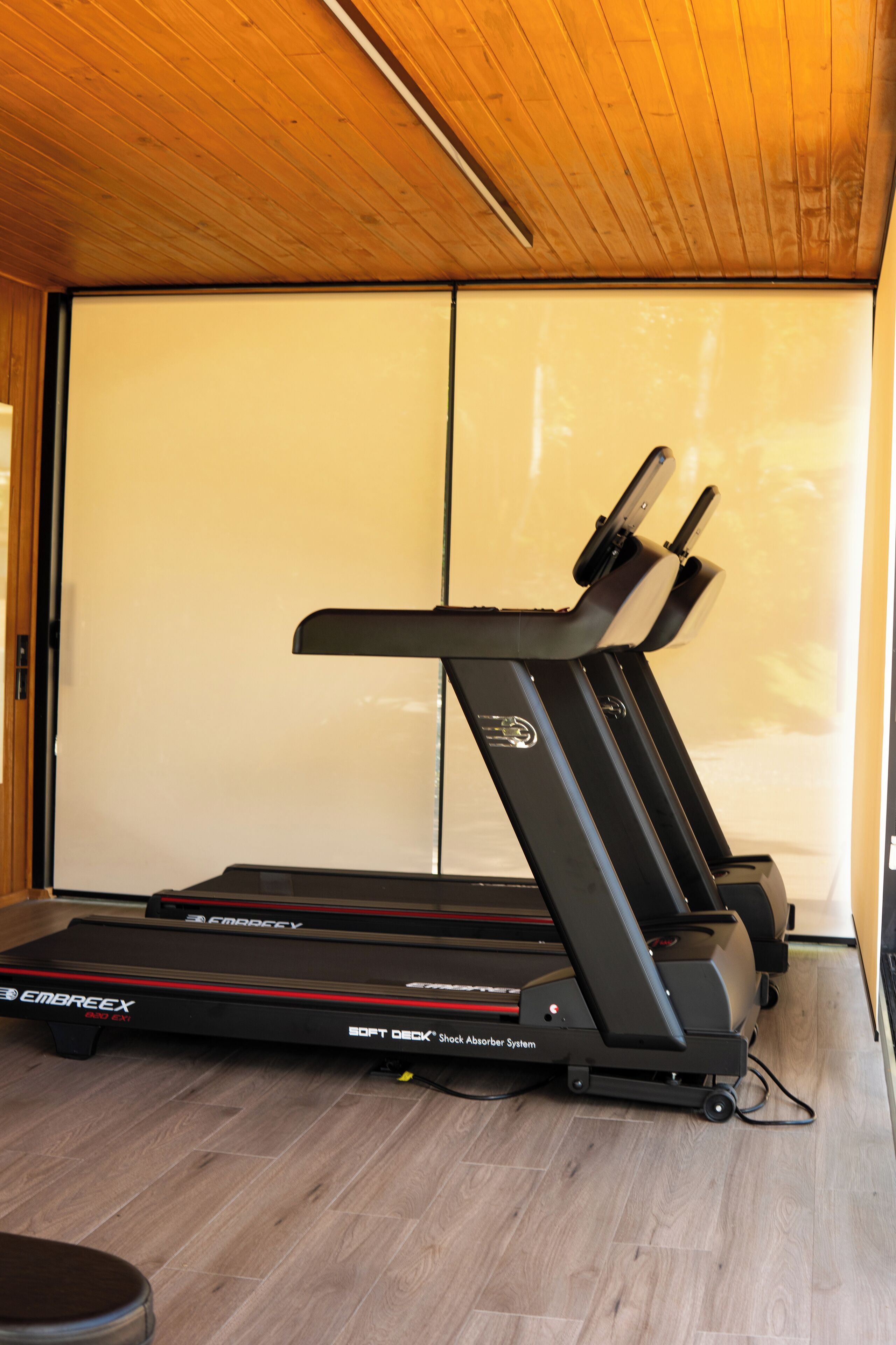 Un tapis de course dans une pièce dont le sol est en bois, avec une porte coulissante à l’arrière-plan.