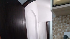 A kitchen with a tiled backsplash, a countertop with a jar of snacks, and a door leading to another room. - Rua Anápolis (Guarulhos)