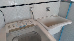 A compact washer and sink unit with a control panel, a transparent washing drum, and a blue pipe. - Rua Anápolis (Guarulhos)