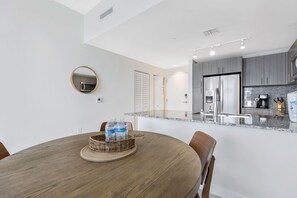A modern kitchen with grey cabinets, stainless steel appliances, and a granite countertop.