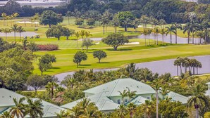 A golf course with multiple holes, palm trees, and a water body.