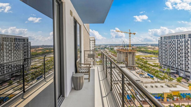 A balcony with a view of a construction site, a crane, and surrounding buildings.