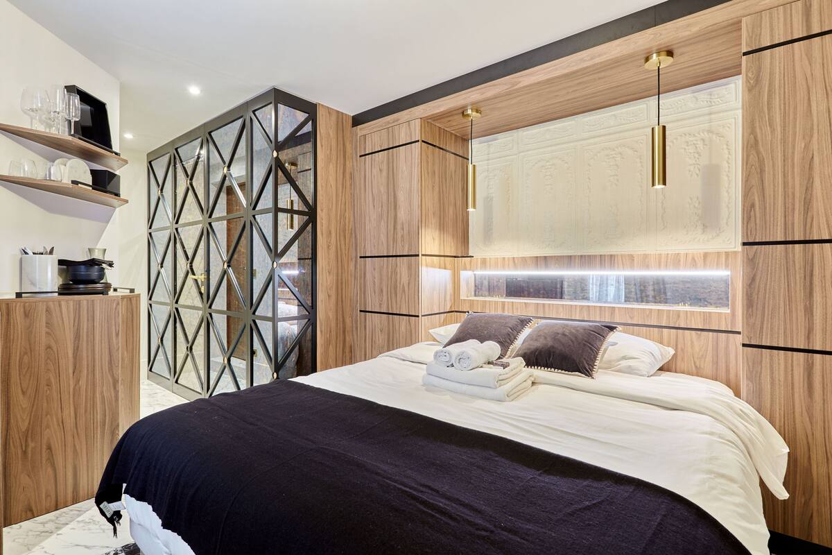 A modern bedroom with a large bed, wooden headboard, and built-in shelves.