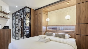 Una habitación de hotel moderna con una cama grande, paneles de madera, un diseño geométrico en la pared y un aplique empotrado.