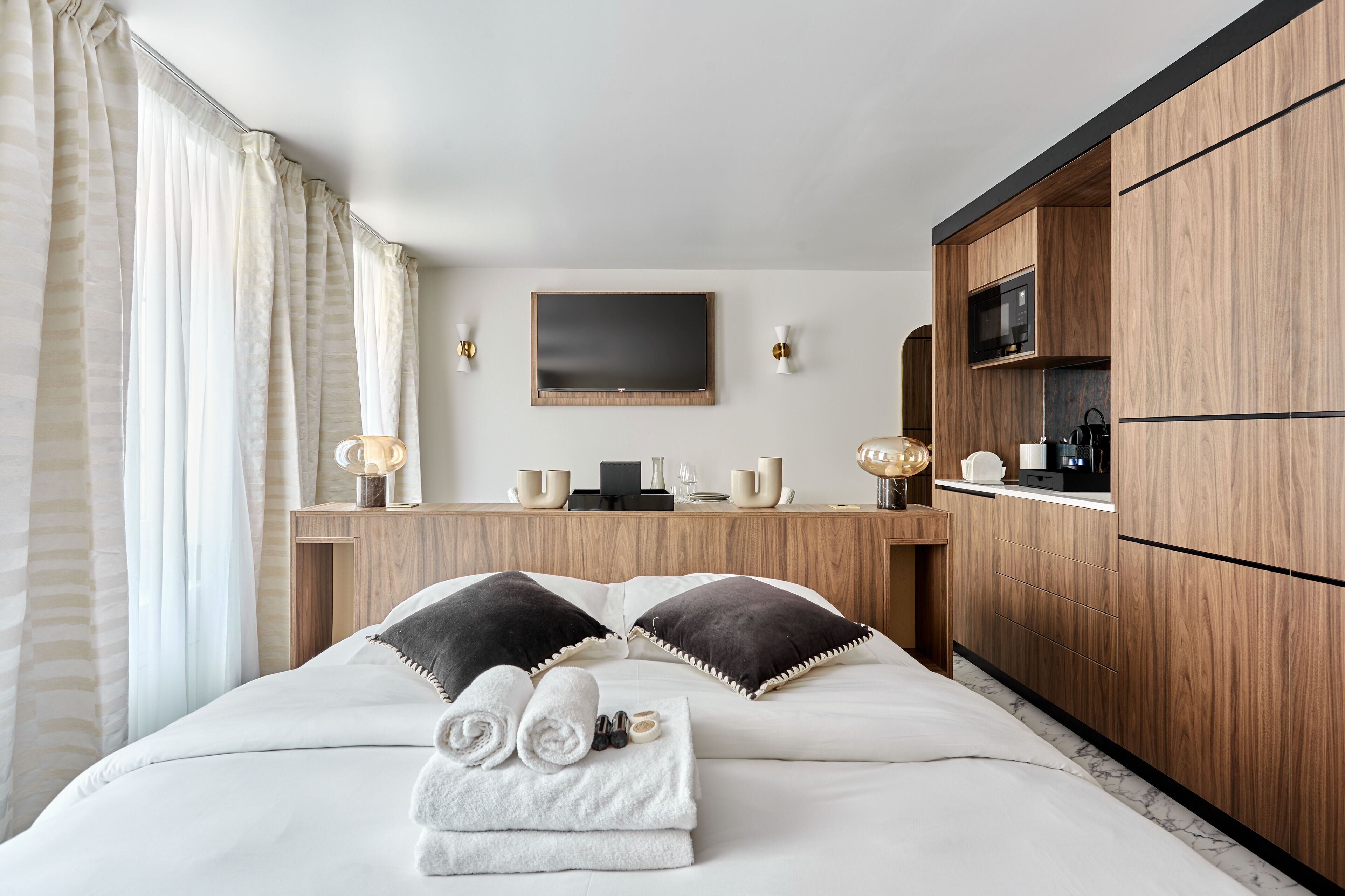 Ein Hotelzimmer mit Bett, einem Holztisch, einem Flachbildfernseher und einer Mikrowelle.