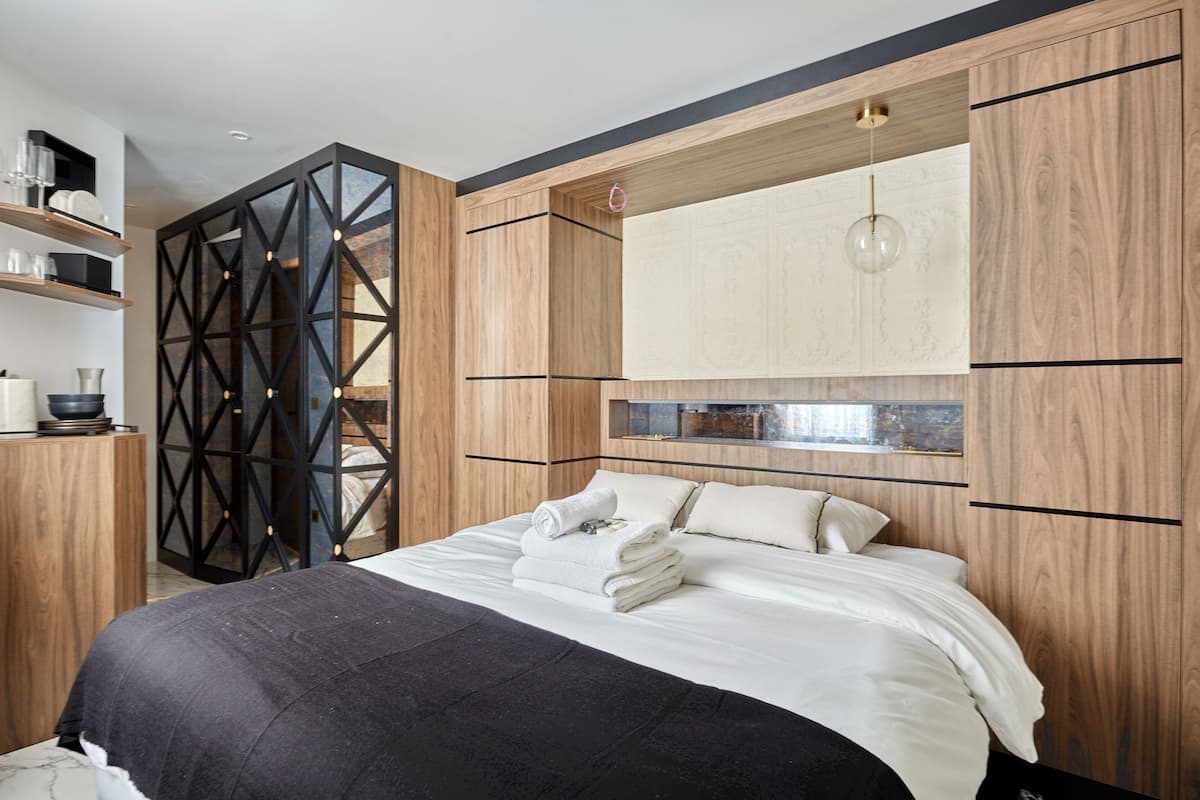 A modern bedroom with a large bed, wooden cabinetry, and built-in shelves.