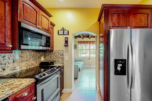 A kitchen with wooden cabinets, a stainless steel refrigerator, a microwave, and an oven.