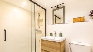 A modern bathroom with a glass shower enclosure, a wooden vanity with a sink, and a toilet. - Charming apartment in Gentilly-  door of Paris (Gentilly)