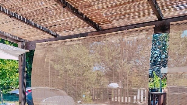 A covered outdoor seating area with wooden railings and a woven privacy screen. - Spacious chalet with furnished terrace (Fréjus)