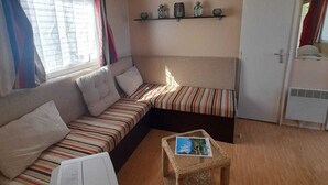A living room with a sofa, a coffee table, and a washing machine. - Spacious chalet with furnished terrace (Fréjus)