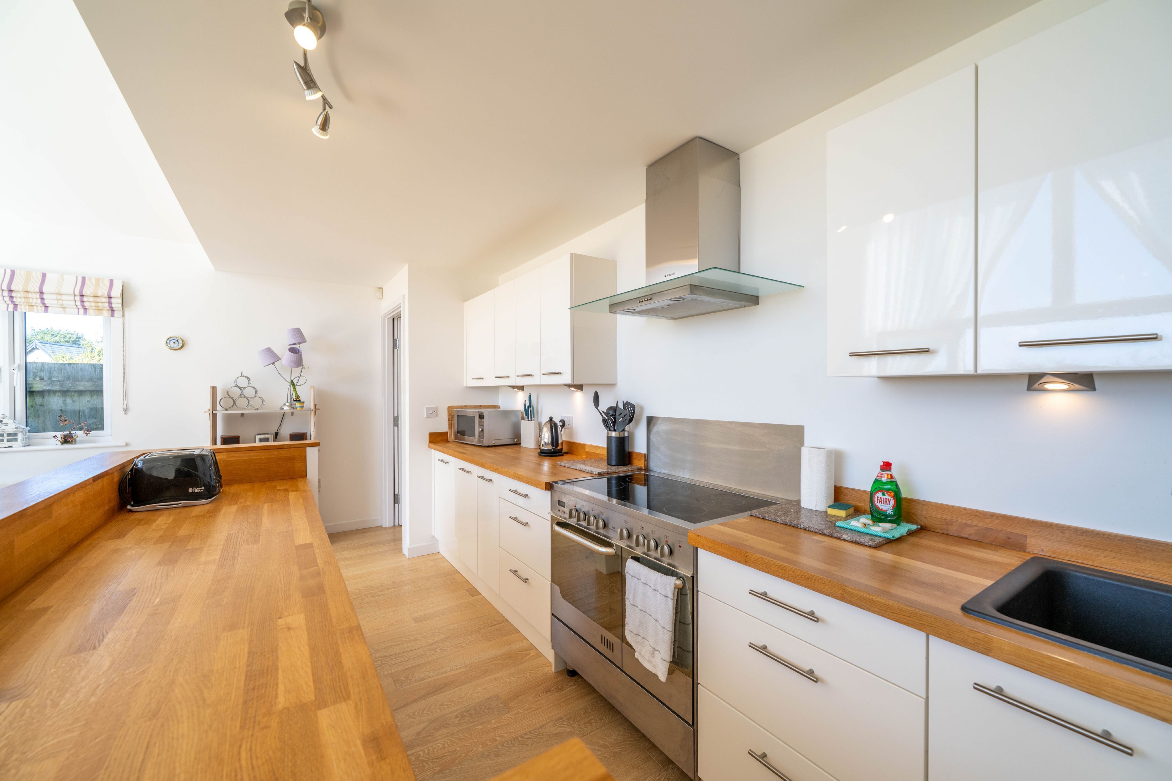 A modern kitchen with white cabinets, a stainless steel stove, and a wooden countertop.