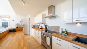 A modern kitchen with white cabinets, a stainless steel stove, and a wooden countertop. - The Sheiling - Three Bedroom House, Sleeps 6 (Woolacombe)