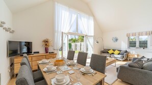 A modern living space with a dining area, a sofa, and a TV. - The Sheiling - Three Bedroom House, Sleeps 6 (Woolacombe)