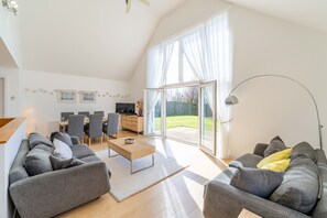 A spacious living area with a sofa, coffee table, and a dining table set up. - The Sheiling - Three Bedroom House, Sleeps 6 (Woolacombe)