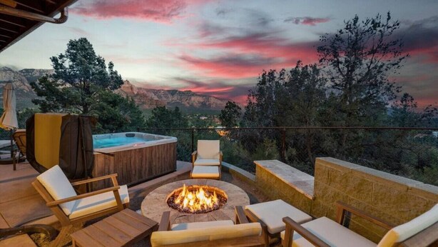 An outdoor seating area with a fire pit, lounge chairs, and a hot tub overlooking a scenic landscape. - Uptown Home w/ Amazing Views and Hot Tub (Sedona)