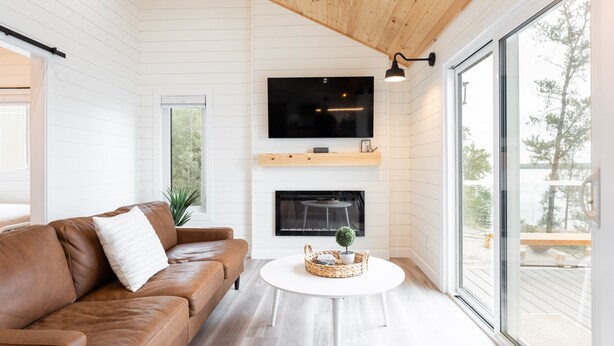 A modern living room with a brown leather sofa, a white coffee table, and a flat-screen TV mounted on the wall.