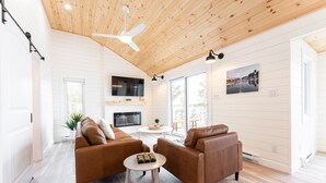 A modern living room with two brown leather sofas, a white coffee table, and a ceiling fan.