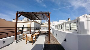 A rooftop terrace with a wooden pergola, seating area, and a view of surrounding buildings. - Apto Plus 1 Dorm. Int. 1ª Planta (Cádiz)