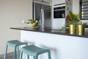 Una cocina moderna con una isla central, taburetes de bar y plantas decorativas.