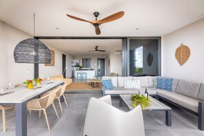Un salon moderne comprenant un coin repas, un ensemble de canapés et un ventilateur de plafond.