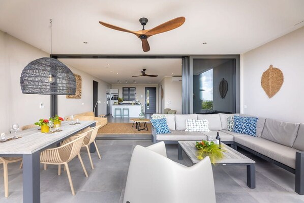 A modern living room with a dining area, a sofa set, and a ceiling fan.