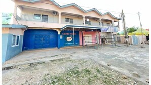 Un edificio de varios pisos con una puerta de garaje azul, un letrero que dice 'Latex Foam' y un balcón.