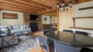Una sala acogedora con chimenea, un sofá y una mesa de comedor con sillas.