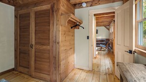 Un interior de madera con una puerta grande de madera, un banco y una estructura de techo de madera.