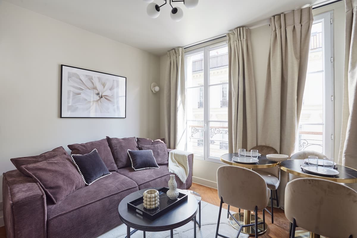 A modern living room with a sofa, coffee table, and dining area.