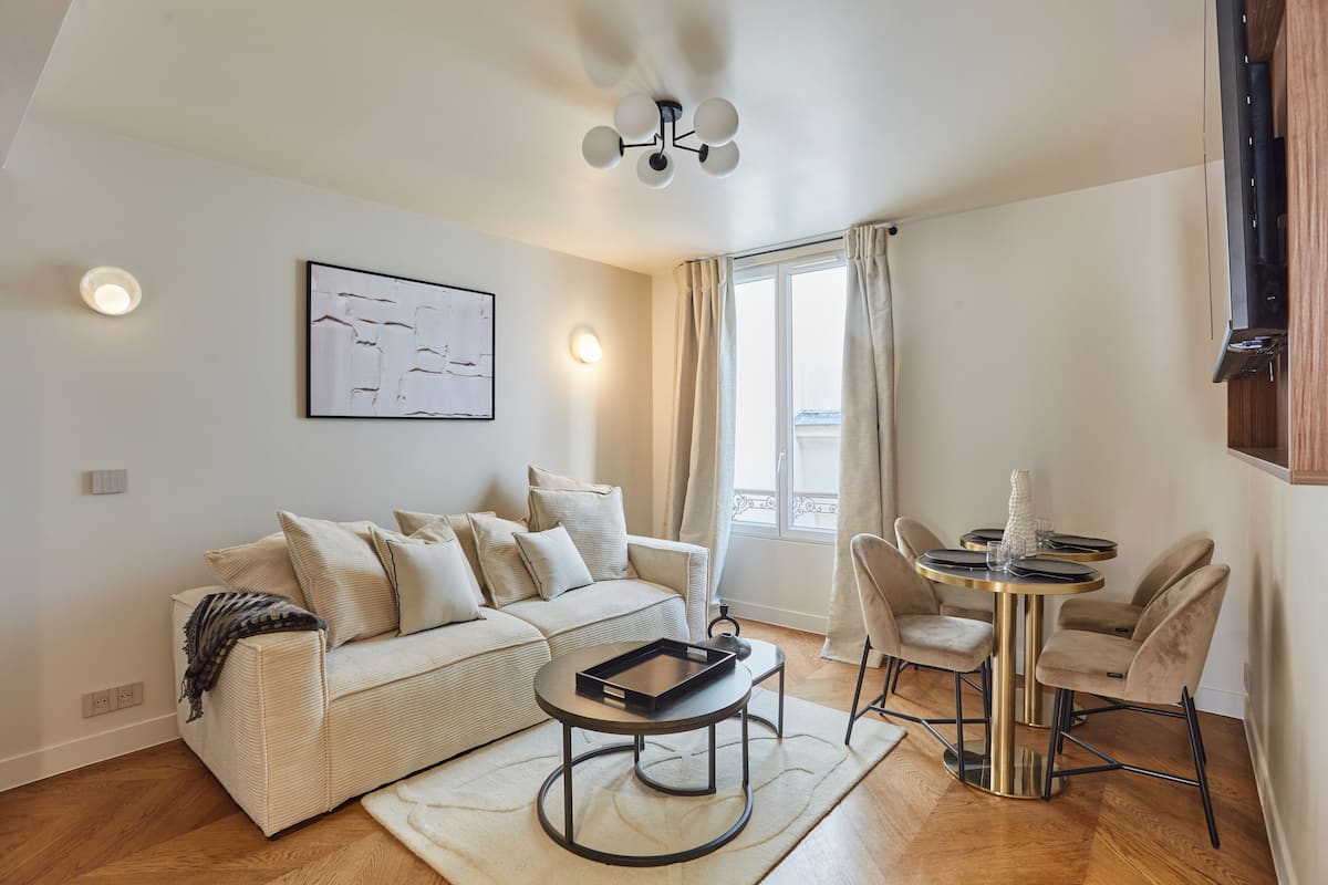 A modern living room with a sofa, a coffee table, and a dining area with chairs and a table.