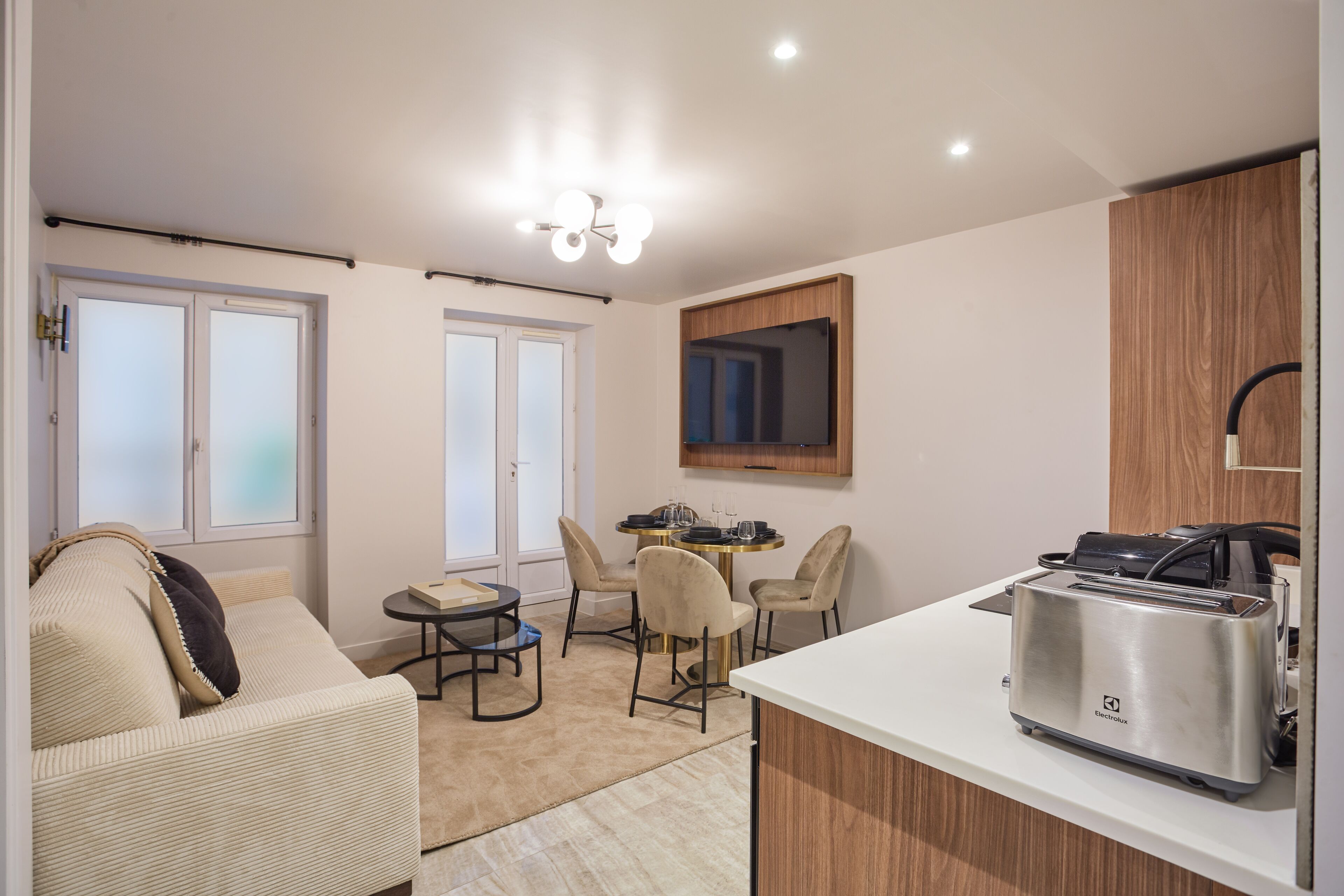 A modern kitchen with a toaster, a dining area with chairs and a small table, and a sofa with a cushion.