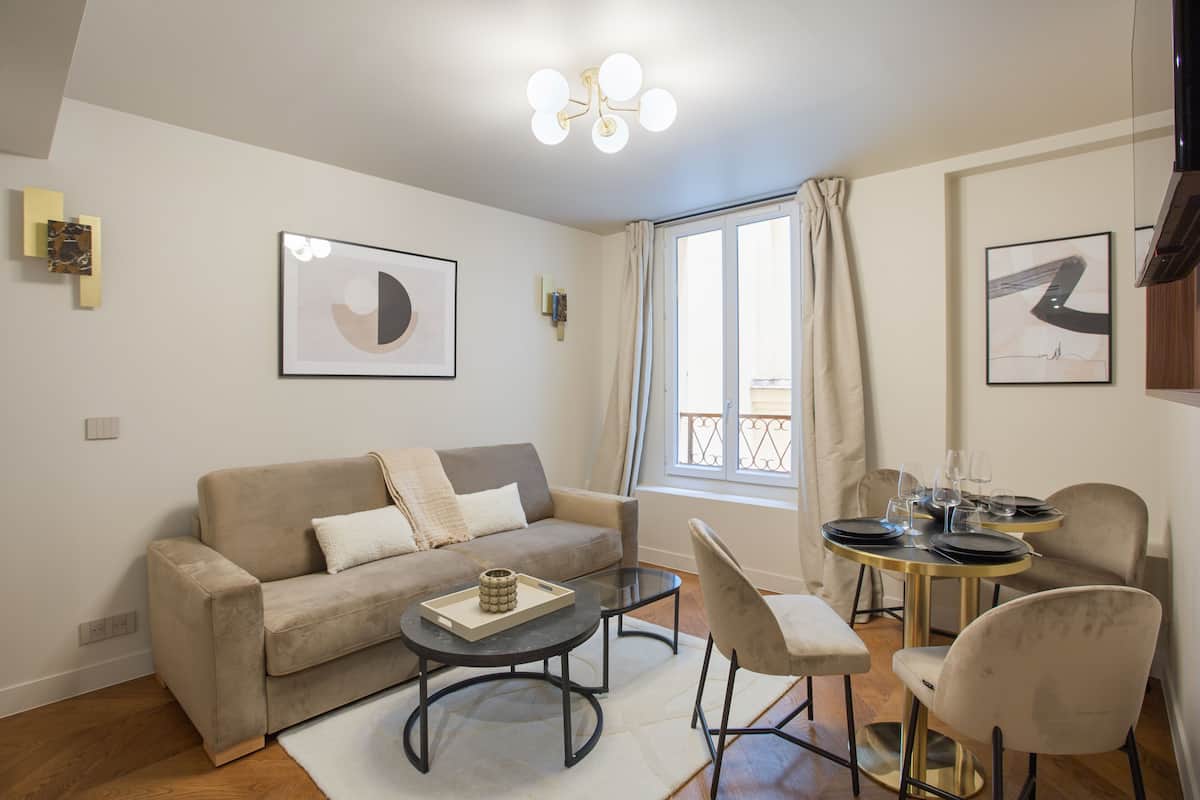 A modern living room with a sofa, coffee table, and dining area with chairs and a table.