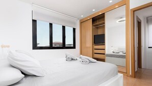 Um quarto moderno com uma cama grande, televisão e closet espaçoso.