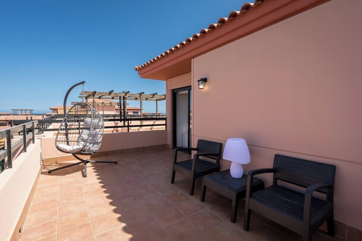 A balcony with a chair, a table, and a lamp.