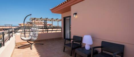 A balcony with a chair, a table, and a lamp.